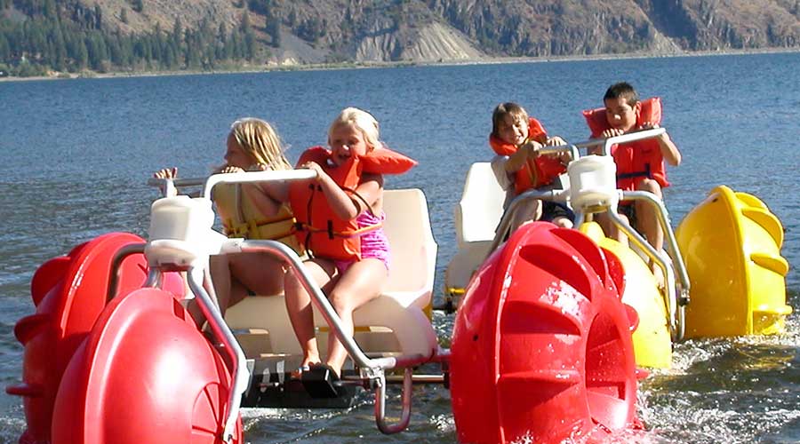 Yellow and red Aqua-Cycle™ Water Trikes at a lake resort or youth camp